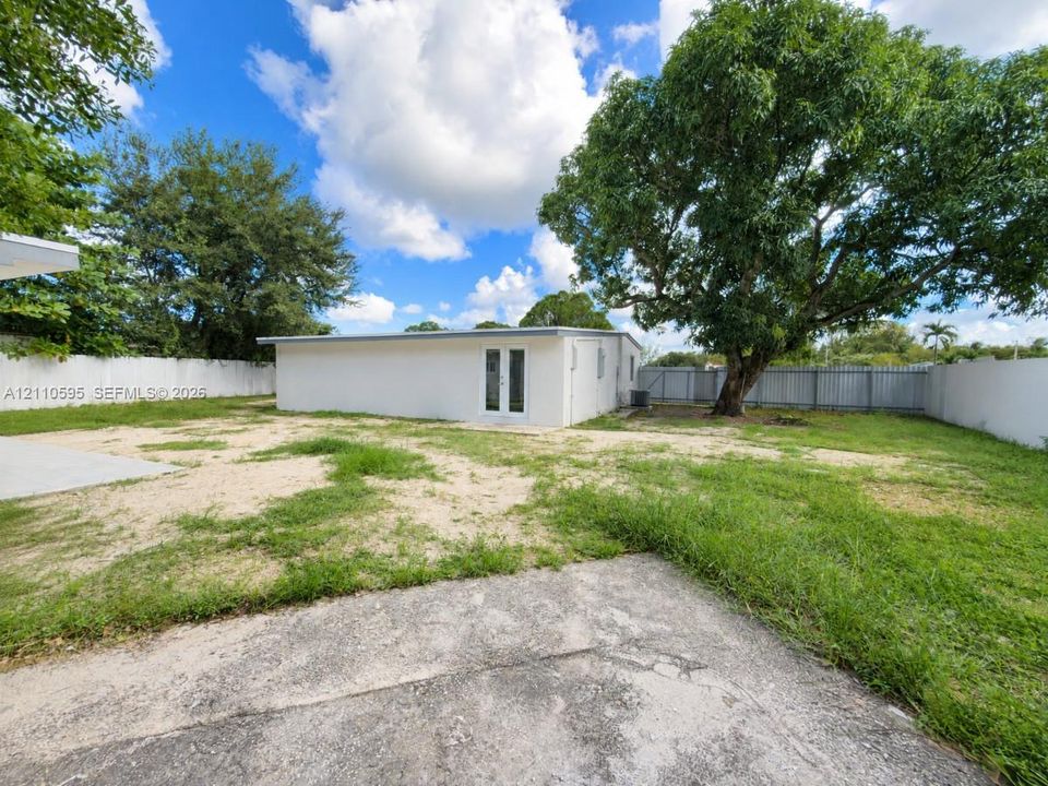 Expansive backyard featuring a concrete patio, perimeter privacy fencing, and mature trees