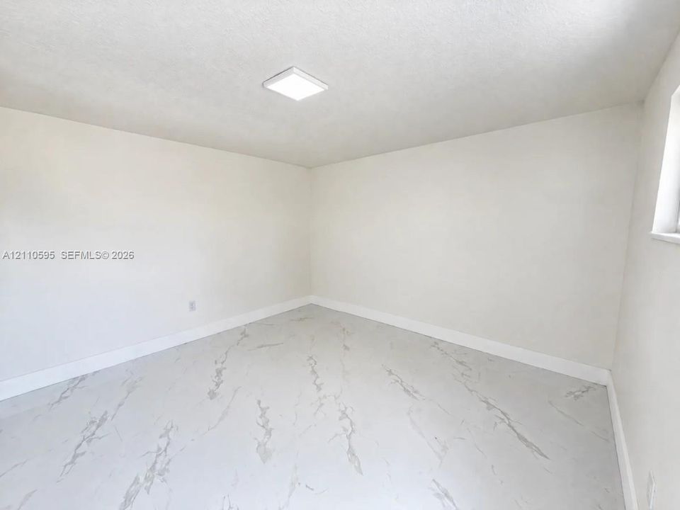 Neutral-toned room featuring large-format tile flooring with a veined pattern, smooth interior walls, and a recessed LED ceiling light