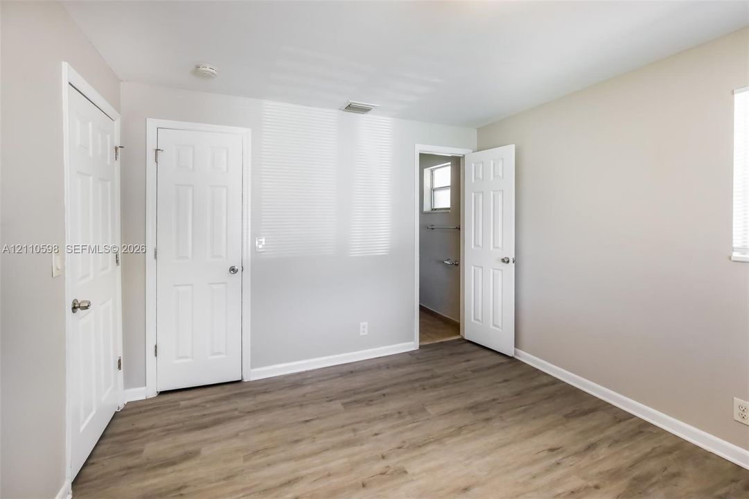 Neutral-toned interior featuring wood-finish flooring, six-panel doors, and natural light via recessed windows