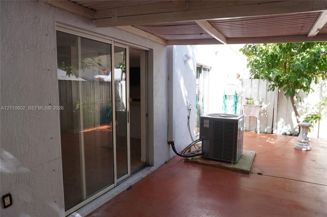 Covered patio area featuring a concrete surface, sliding glass door, and perimeter fencing