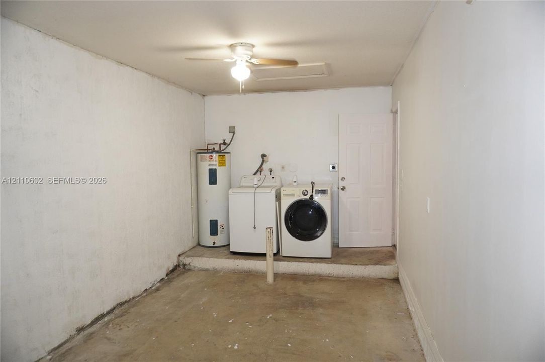 Utility space featuring a water heater, washer and dryer hookups, overhead ceiling fan with lighting, and a solid-core six-panel door