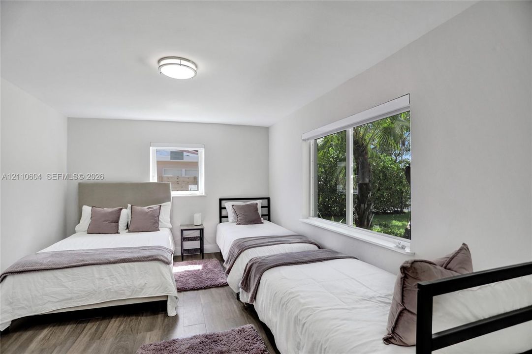 Neutral-toned interior featuring wood-finish flooring, crisp white walls, flush-mount ceiling lighting, and large windows