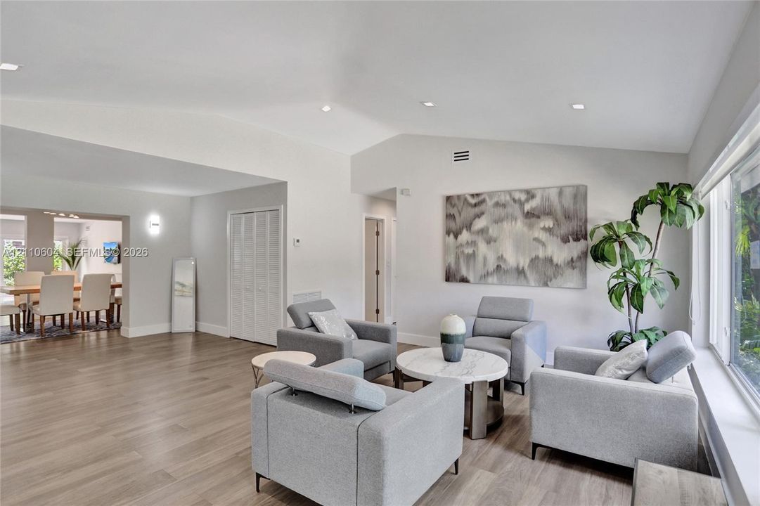 Open-concept interior featuring vaulted ceilings, wood-finish flooring, recessed lighting, and large windows