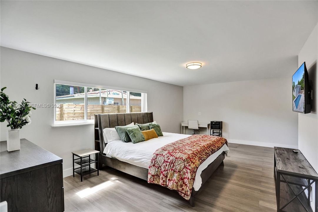 Neutral-toned interior featuring wood-finish flooring, a flush-mount light fixture, and a large horizontal window