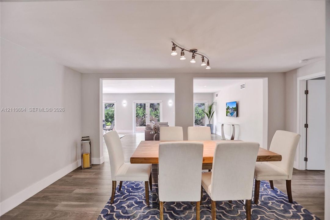 Wood-finish flooring, neutral wall tones, multi-light track lighting fixture, and dual wide openings