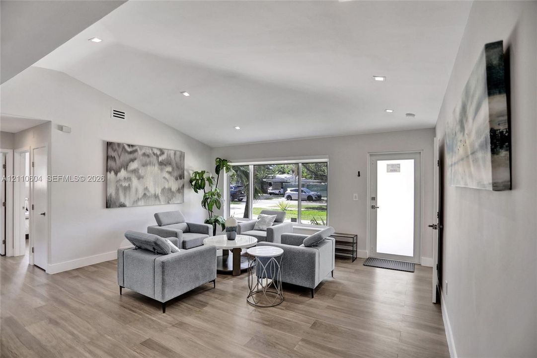 Vaulted ceilings, wood-finish flooring, recessed lighting, and a large picture window