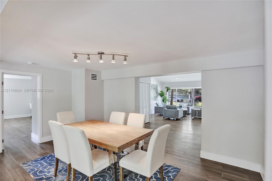 Wood-finish flooring throughout, five-bulb track lighting fixture, and large multi-pane windows