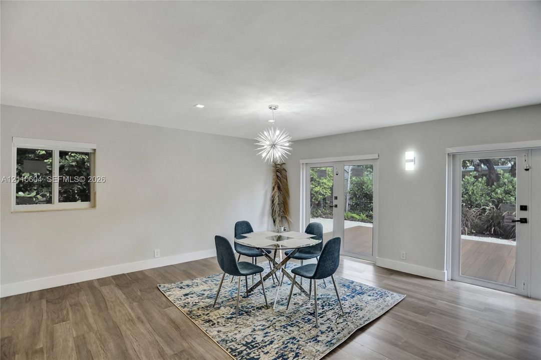 Open-concept space featuring wood-finish flooring, a starburst chandelier, recessed lighting, and double glass-paneled doors