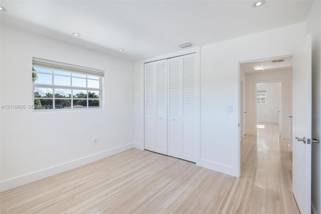 Light-filled room featuring wood-finish flooring, recessed lighting, double louvered closet doors, and multi-pane window