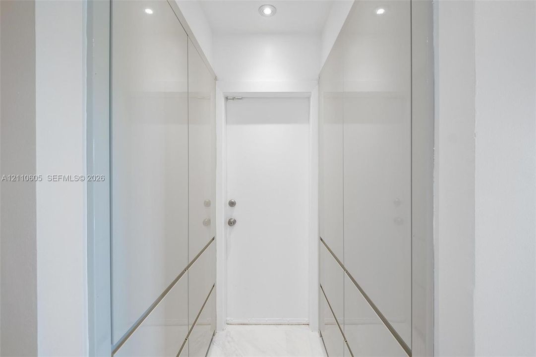 Floor-to-ceiling high-gloss cabinetry with integrated hardware, recessed ceiling lighting, and stone-finish flooring