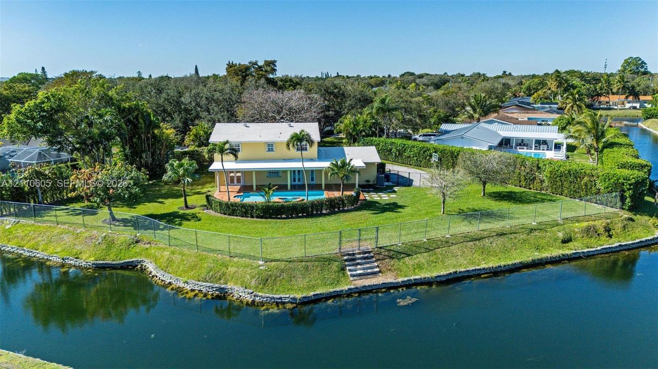 Two-story residence featuring a waterfront lot, inground swimming pool, covered rear porch, and fenced perimeter