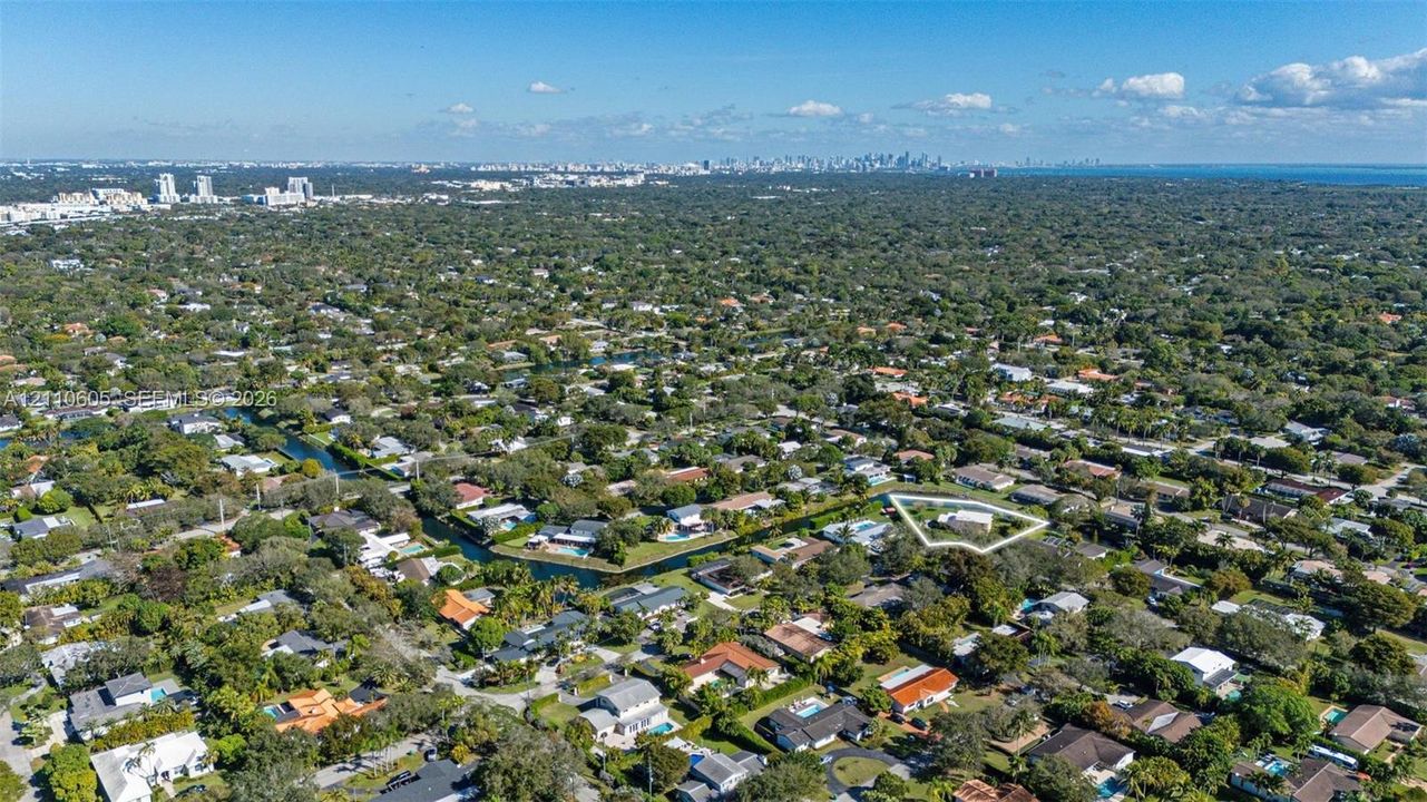 Aerial perspective of a residential property featuring a large lot, perimeter landscaping, and proximity to a canal