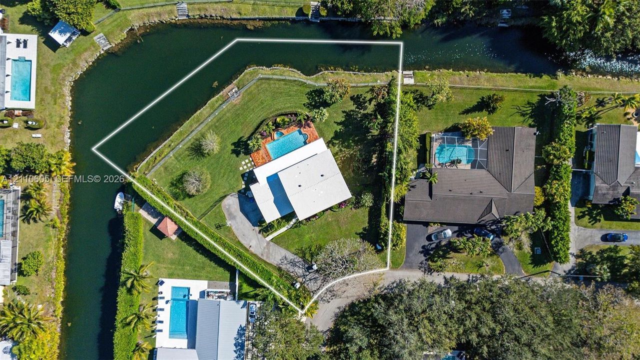 Corner lot property featuring expansive grounds, a swimming pool with a patio surround, and direct water frontage