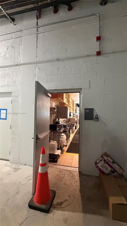 Painted concrete block walls featuring exposed electrical conduit and a commercial-grade steel door with panic hardware