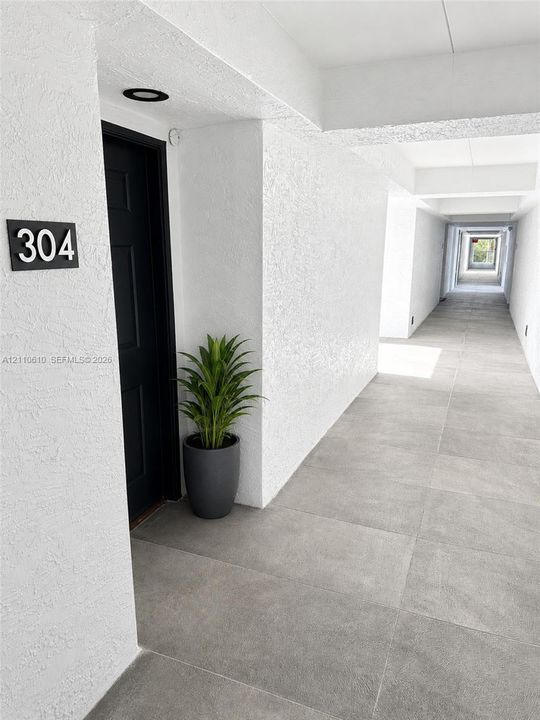 Entryway featuring a solid dark-toned door, textured white wall finishes, large-format grey tile flooring, and recessed ceiling lighting
