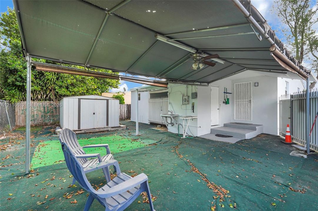 Outdoor area featuring a covered patio with an integrated ceiling fan, an exterior utility sink, and a detached metal storage shed