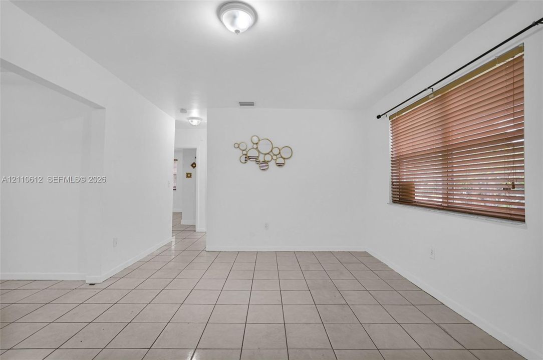 Neutral-toned tile flooring, flush-mount ceiling lighting, and horizontal window blinds