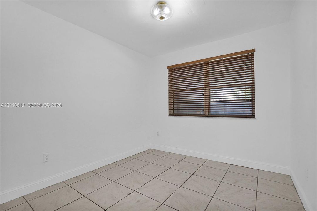 Neutral-toned tile flooring, flush-mount dome lighting, and window with wooden slatted blinds