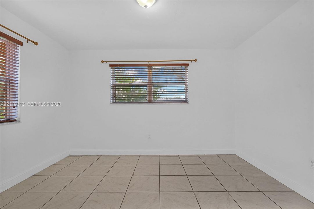 Neutral-toned ceramic tile flooring, crisp white walls, dual windows with fitted horizontal blinds, and a central ceiling-mounted light fixture