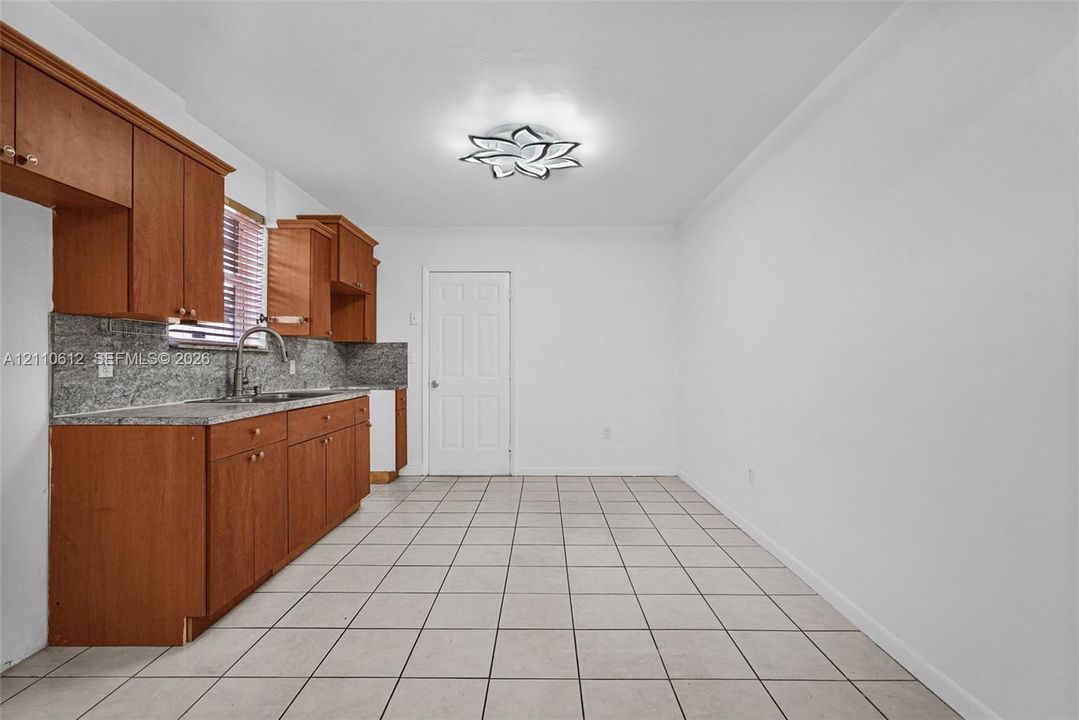 Kitchen featuring wood cabinetry, stone-finish countertops, tile flooring, and a decorative flush-mount ceiling fixture