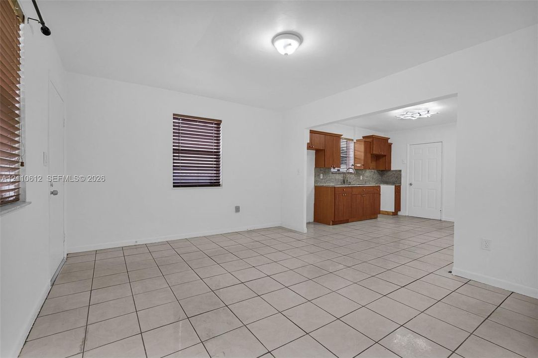Ceramic tile flooring, neutral wall finishes, horizontal slat blinds, and built-in wood-finish cabinetry