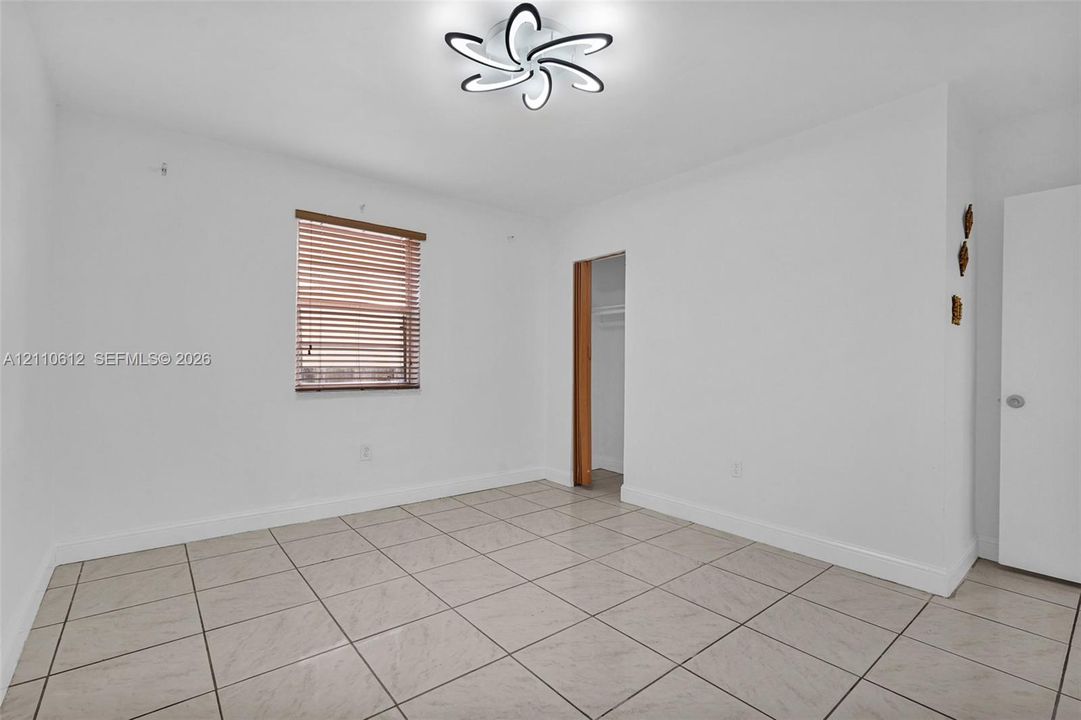 Room featuring neutral ceramic tile flooring, a modern multi-arm flush-mount light fixture, and horizontal window blinds