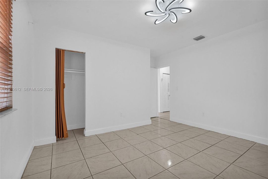 Neutral-toned tile flooring, multi-directional ceiling light fixture, closet with accordion door, and window blinds