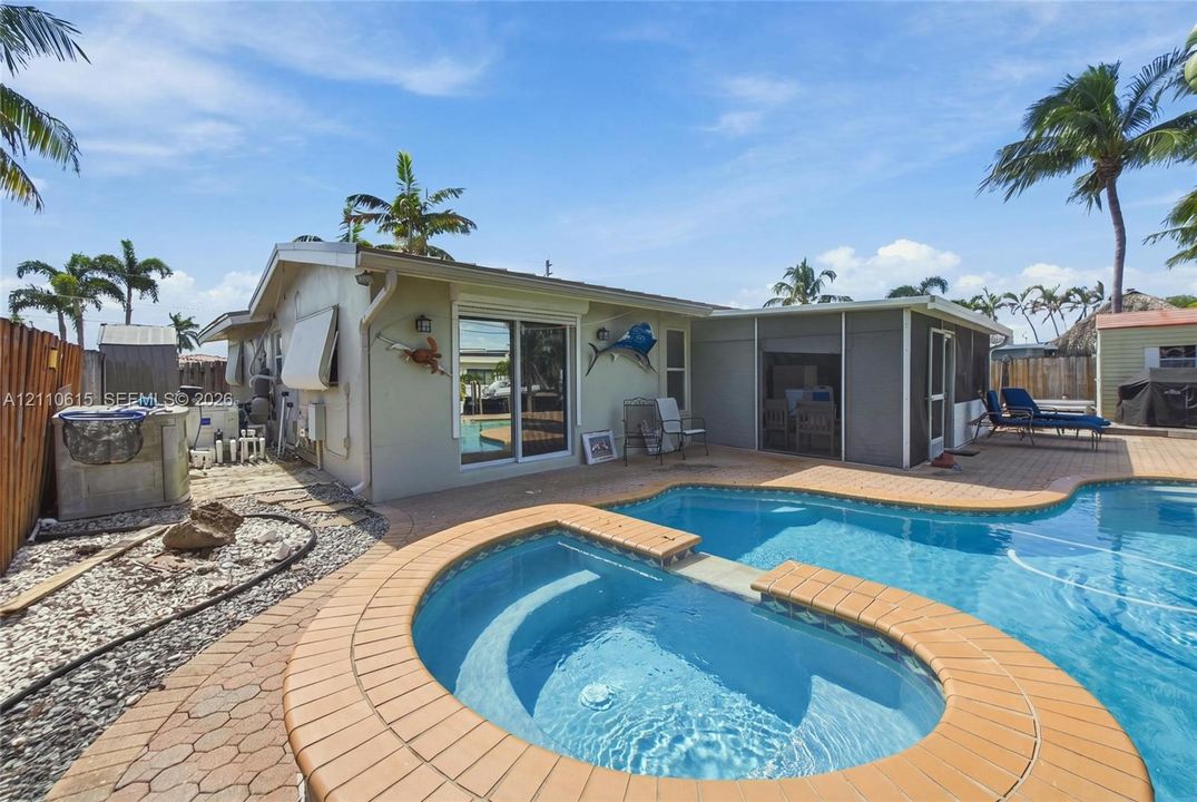 Swimming pool with a raised hot tub and paver stone decking