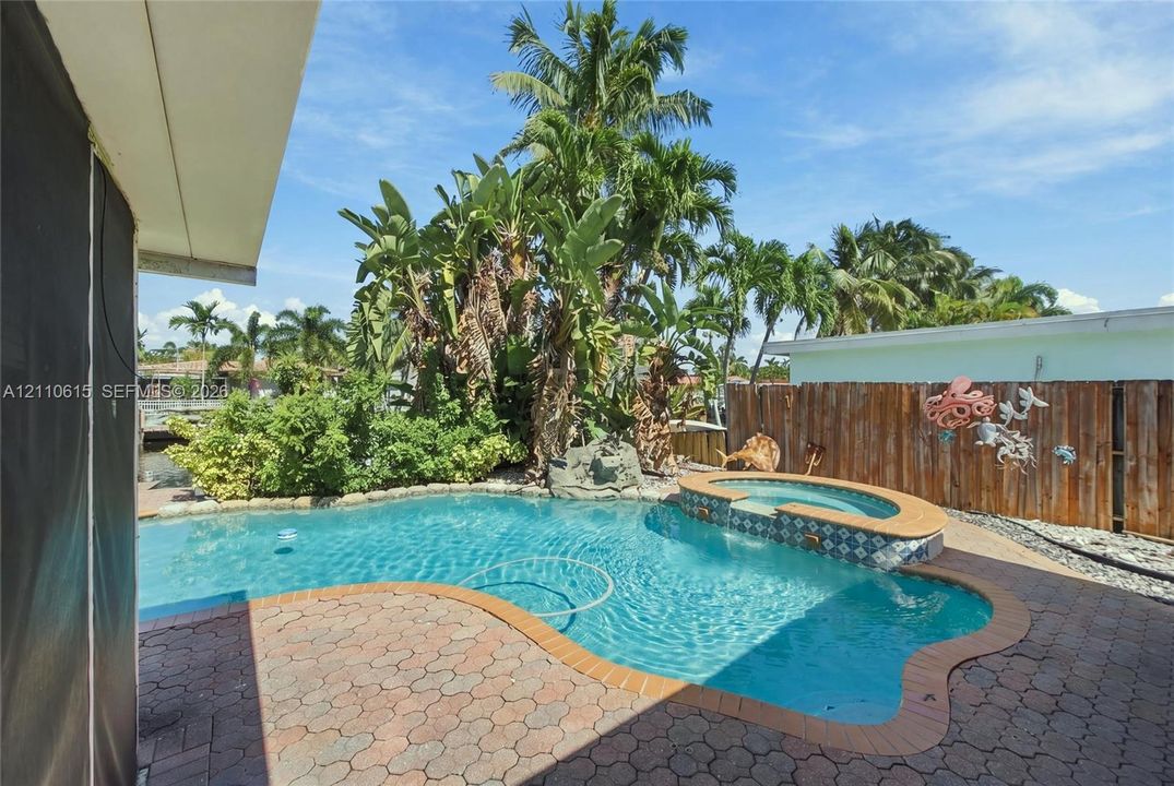 In-ground swimming pool featuring a spillover spa with patterned tile inlay and surround pavers