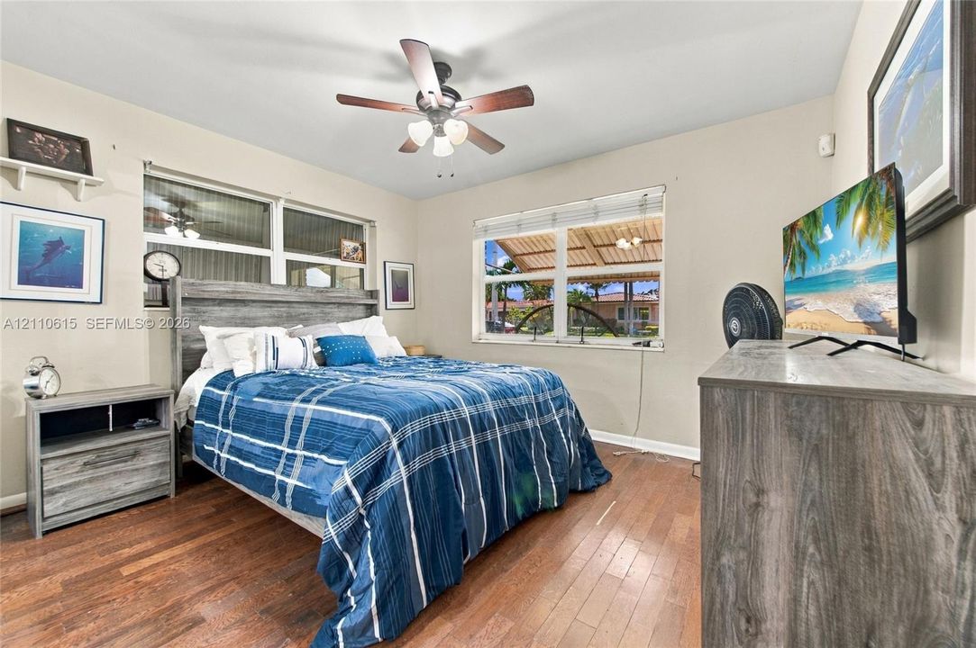 Wood-finish flooring, multi-pane windows with horizontal blinds, and a multi-blade ceiling fan with integrated lighting