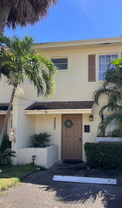 Two-story exterior featuring a light-toned facade, decorative window shutters, a covered entryway, and a built-in concrete planter