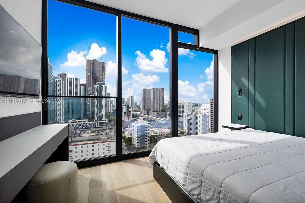 Floor-to-ceiling windows, custom green-paneled feature wall, wood-finish flooring, and built-in minimalist vanity