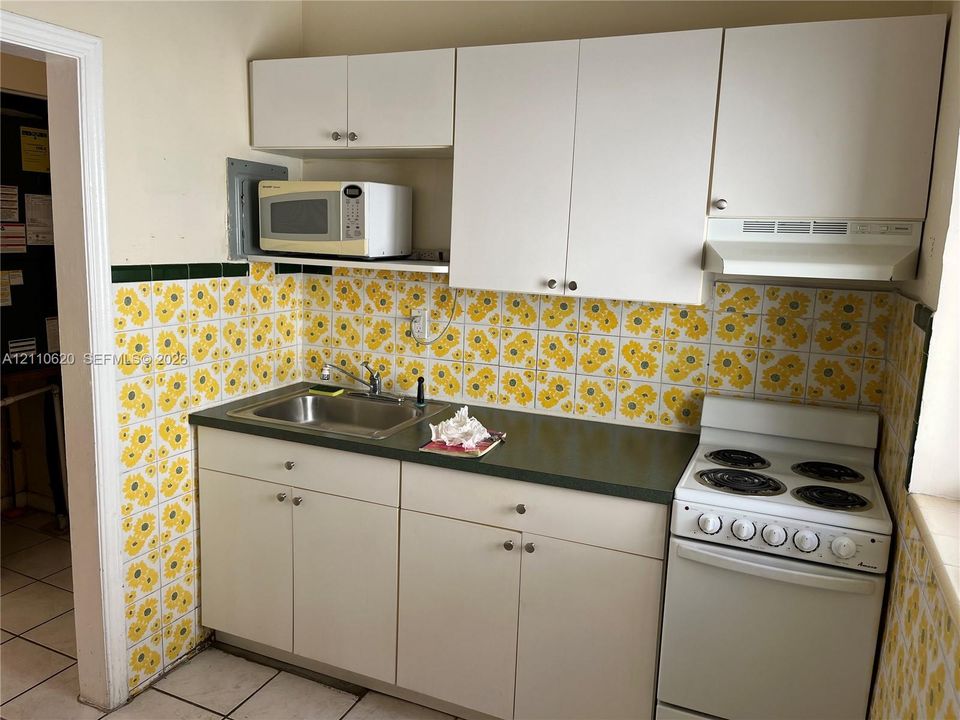 Kitchenette featuring white cabinetry, a single-basin stainless steel sink, a range, and decorative tiled backsplash