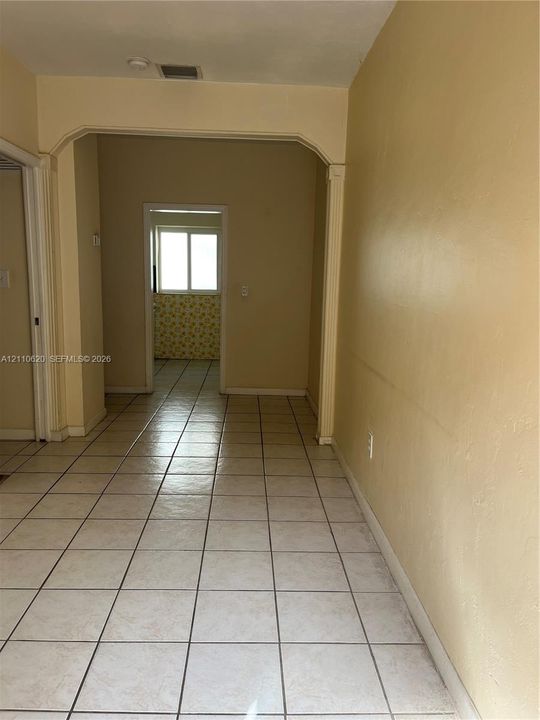 Ceramic tile flooring, arched entryway, and square-pane window