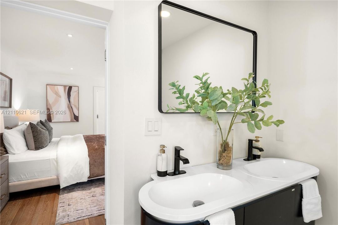Double vanity featuring integrated sinks, quartz countertop, matte black faucets, and a black-framed mirror