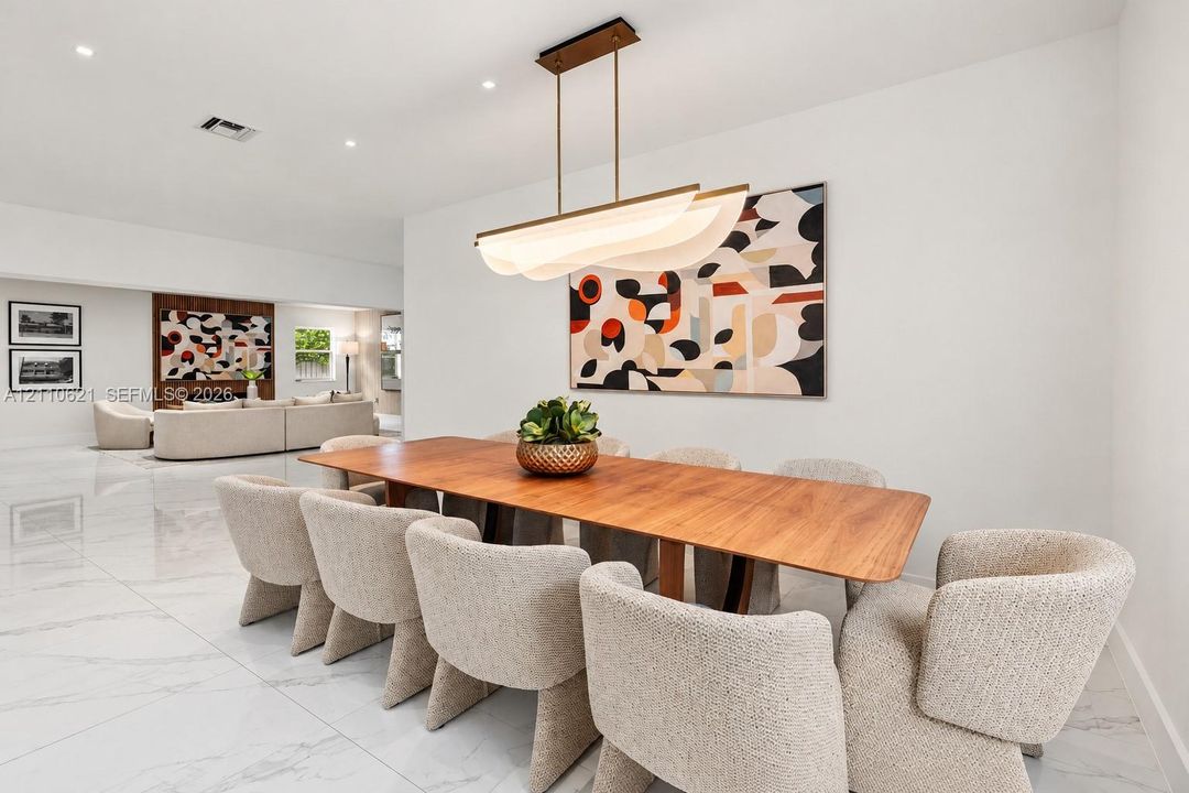 Dining area featuring large-format stone-finish flooring, recessed lighting, and a modern sculptural linear pendant chandelier