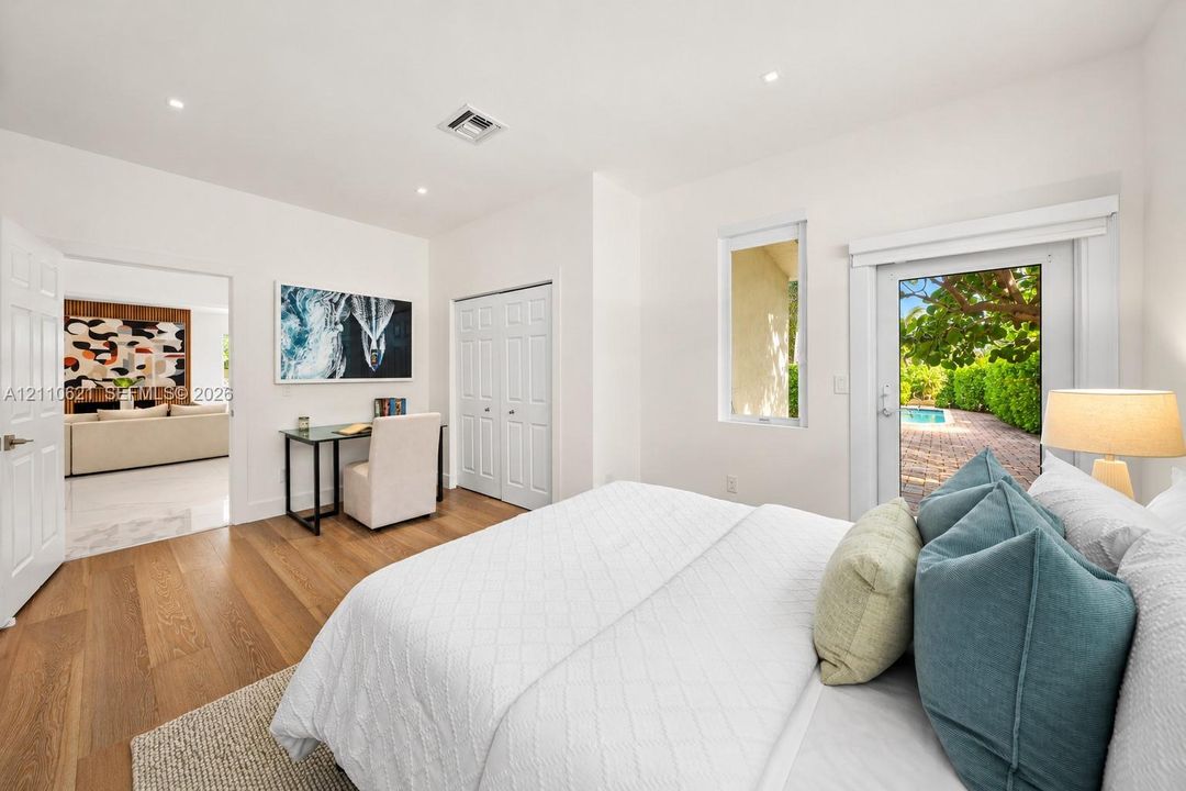 Bedroom featuring wood-finish flooring, recessed lighting, and a glass-paneled door leading to an outdoor brick patio area