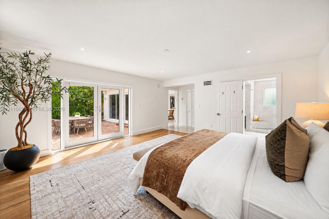 Spacious interior featuring wood-finish flooring, recessed lighting, and white glass-paned double doors opening to an exterior patio