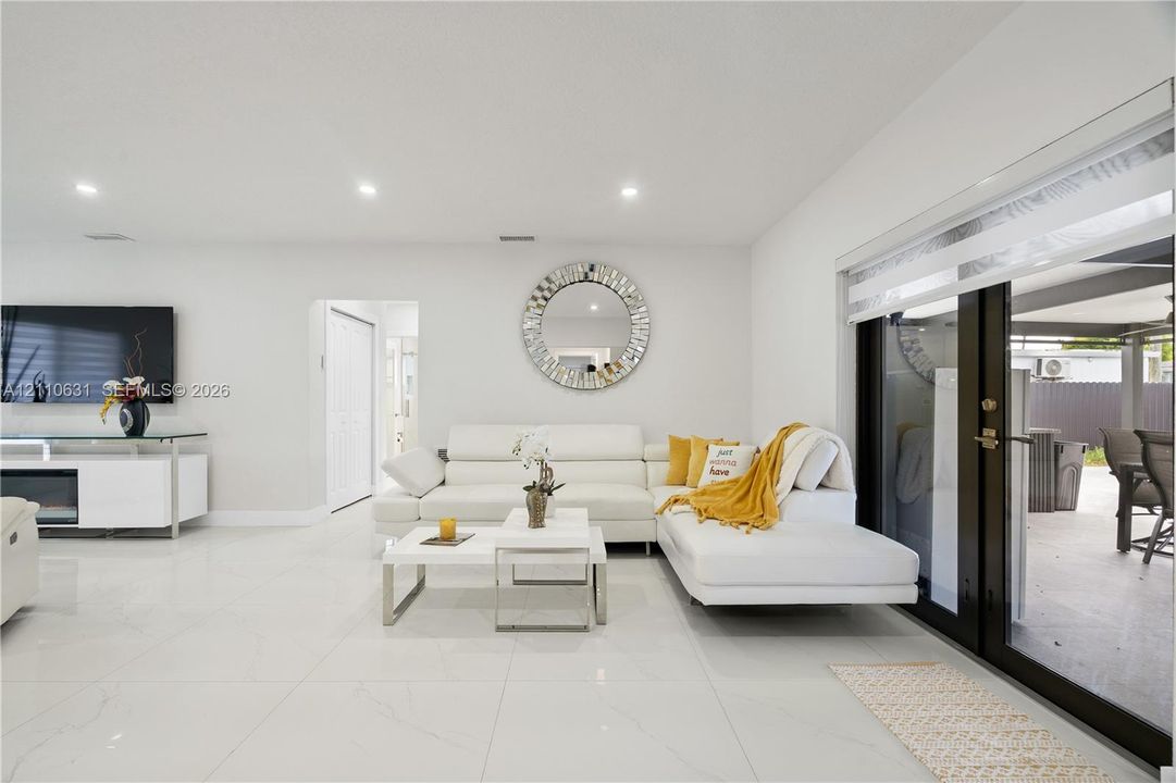 Open-concept interior featuring large-format tile flooring, recessed lighting, and black-framed sliding glass doors