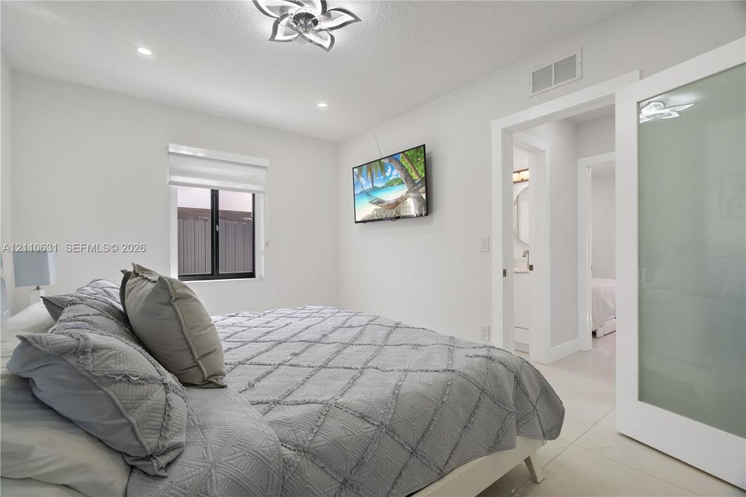 Frosted glass sliding door, recessed ceiling lighting, decorative floral-motif ceiling fixture, neutral tile flooring, and clean-lined interior trim