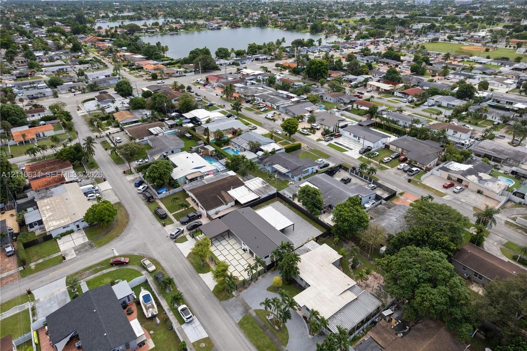 Aerial perspective featuring a residential property with a multi-vehicle driveway, concrete grid patio, and proximity to a large inland lake