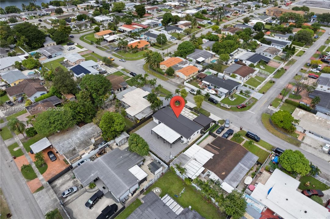 Aerial perspective of a corner lot property featuring a dark-toned roof, an attached covered patio structure, and a fenced perimeter