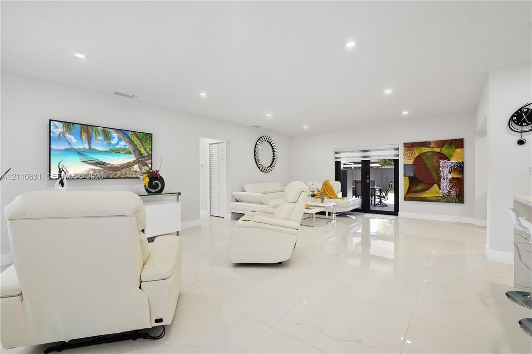 Open-concept interior featuring large-format tile flooring, recessed lighting, and glass-paned double doors