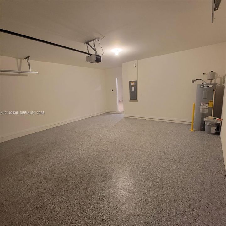 Garage featuring speckled epoxy flooring, a ceiling-mounted automatic door opener, and a dedicated water heater