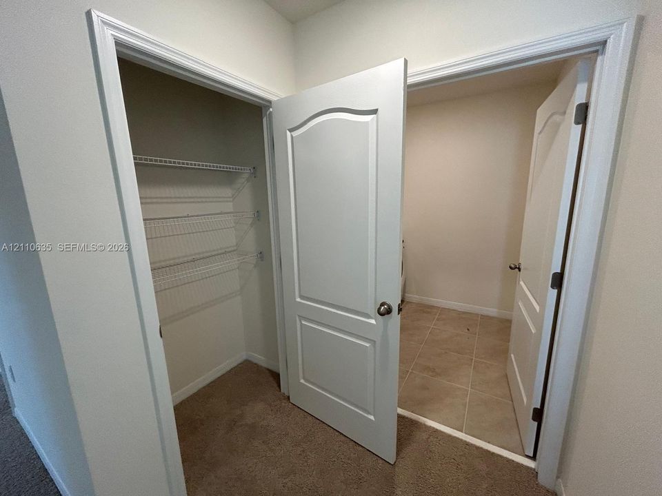 Interior storage area featuring tiered white wire shelving, paneled doors, and carpeted flooring
