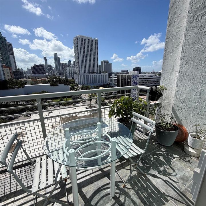 Private balcony with metal mesh railings, stone-tile flooring, and expansive urban skyline scenery