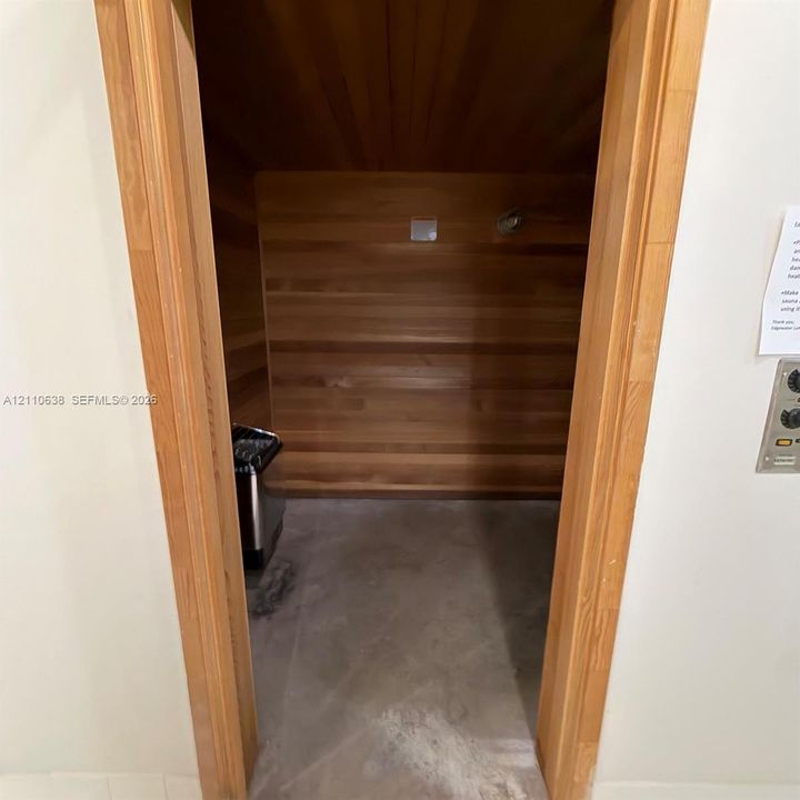 Sauna featuring natural wood-paneled walls, built-in wooden benches, and an integrated heating unit