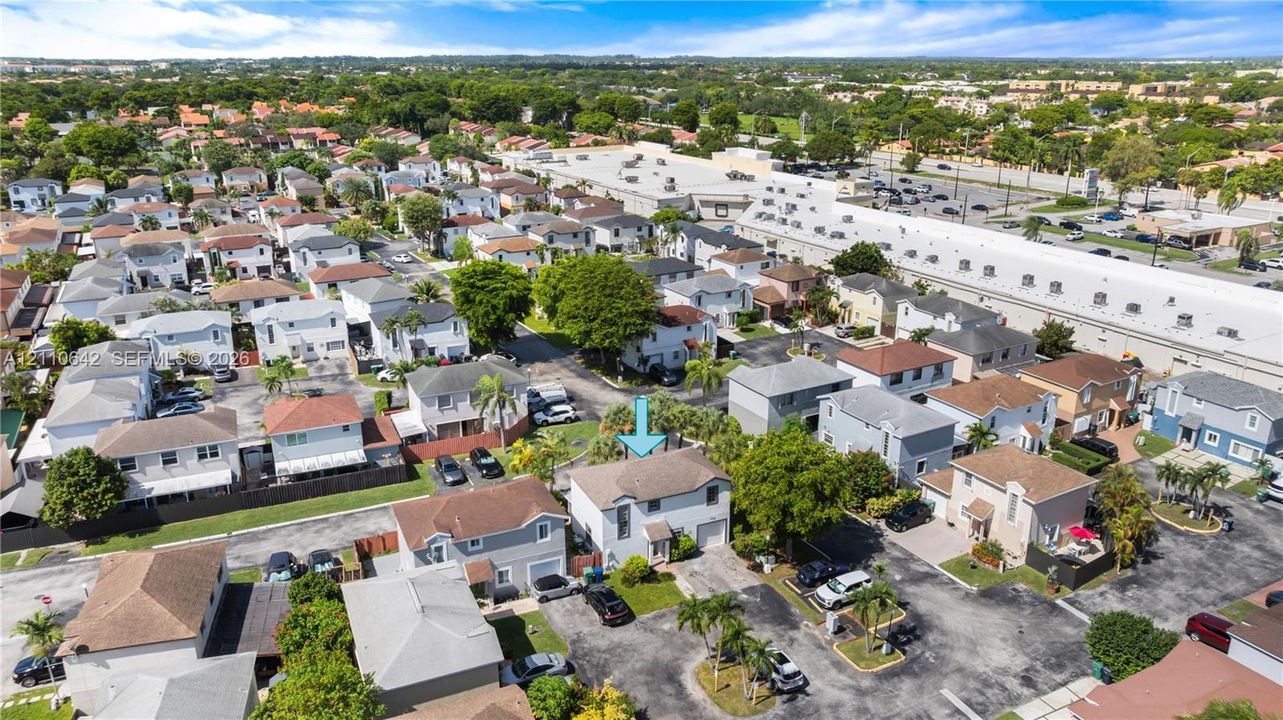 Aerial perspective of a two-story residence featuring a shingled roof, stucco exterior, attached garage, and paved driveway