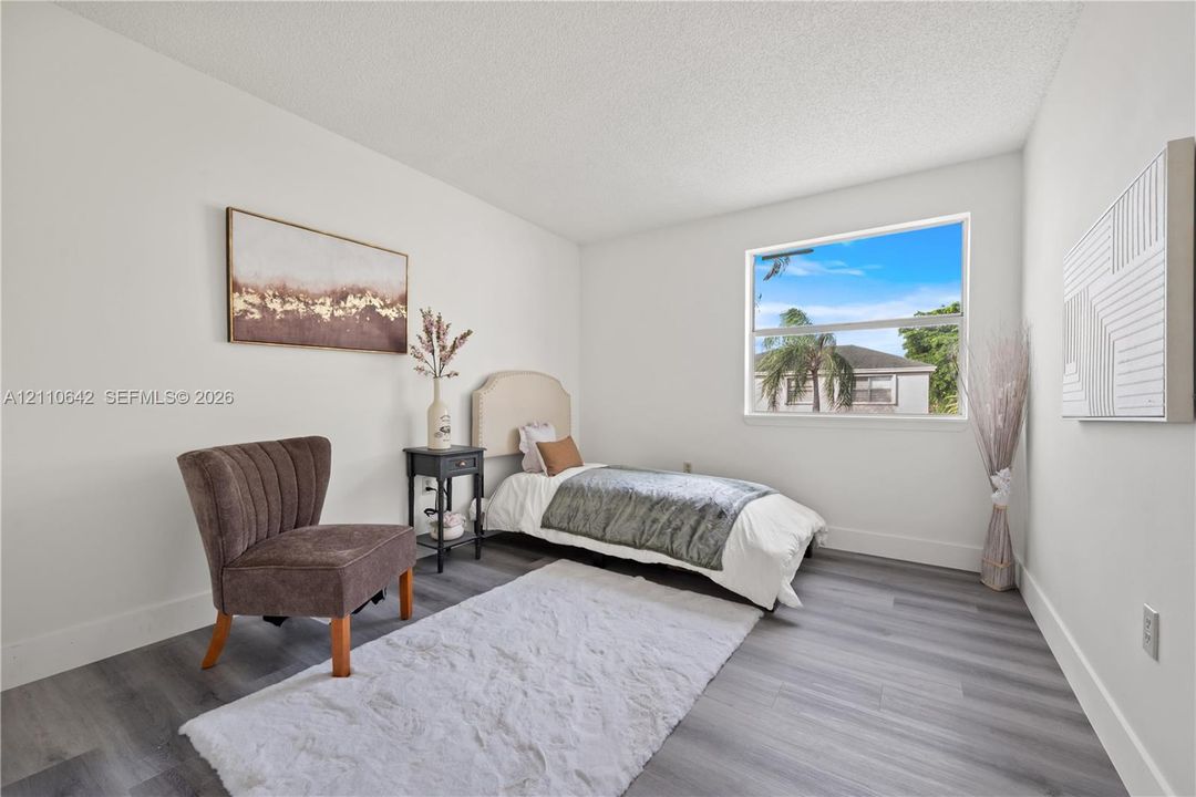 Bedroom featuring wood-finish flooring, white walls, and a large window