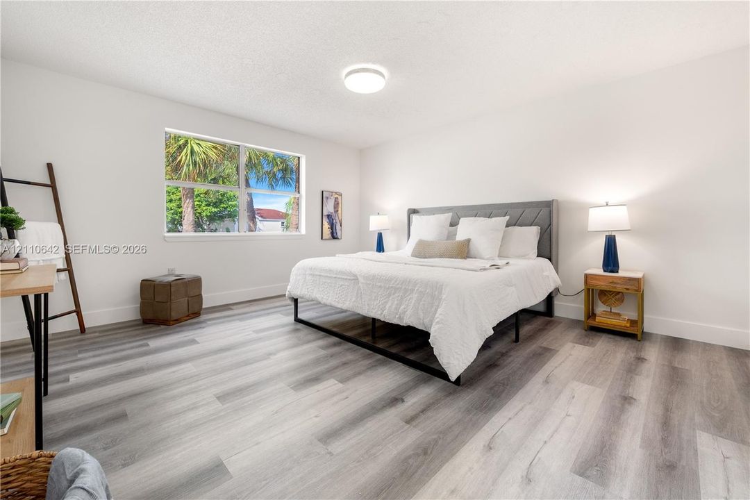 Neutral-toned interior space featuring wood-finish flooring, a large window, and a flush-mount ceiling fixture